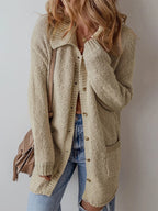 Woman wearing a longline beige textured knit cardigan with a pointed collar and button-up closure.