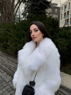 Close-up of a woman's face and shoulders wearing a luxurious white faux fur coat.