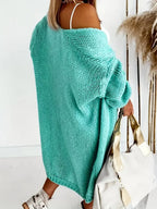Rear view of a woman wearing a longline teal chunky knit cardigan, showing the oversized fit and drop shoulder.