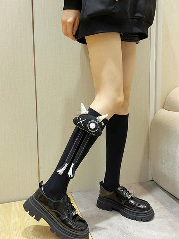 Black knee-high socks with a black fabric applique featuring white horns and dangling legs with white accents