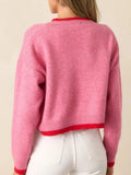 Back view of a woman wearing a pink cropped knit sweater with red trim.
