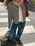 Close-up of a woman wearing a black and white striped cardigan over a white tank top and blue jeans.