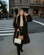 Woman standing on a crosswalk wearing a long brown faux fur coat