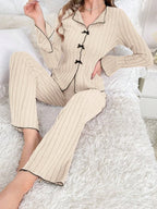 Woman sitting on a bed wearing a cherry print pajama set and holding a mug.