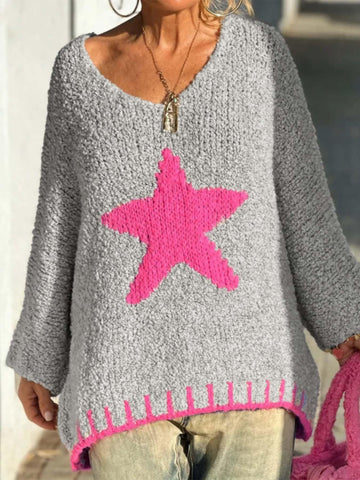 Woman wearing a gray oversized knit sweater with a large pink star graphic on the front and pink trim detail at the hem.