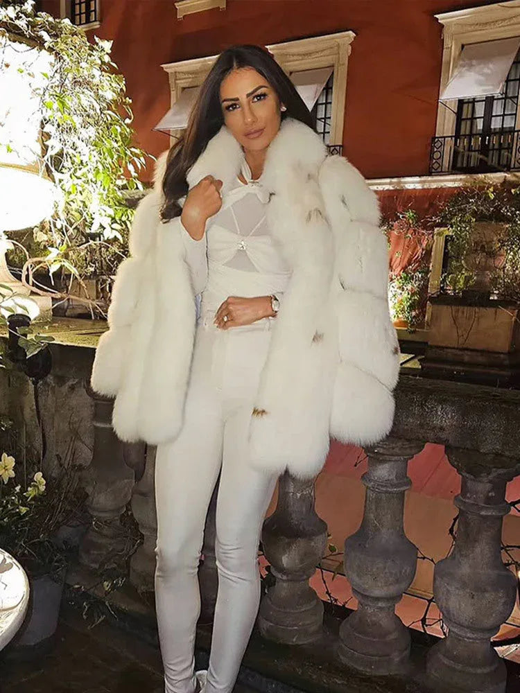 Woman wearing a white oversized faux fur coat with a large collar and full sleeves. Main image