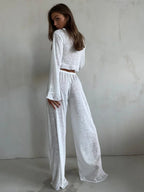 Back view of a woman in a white sheer knit set, featuring the flowy silhouette of the wide-leg pants and cropped top.