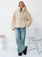 Full body shot of a woman in a beige faux fur cropped jacket and jeans