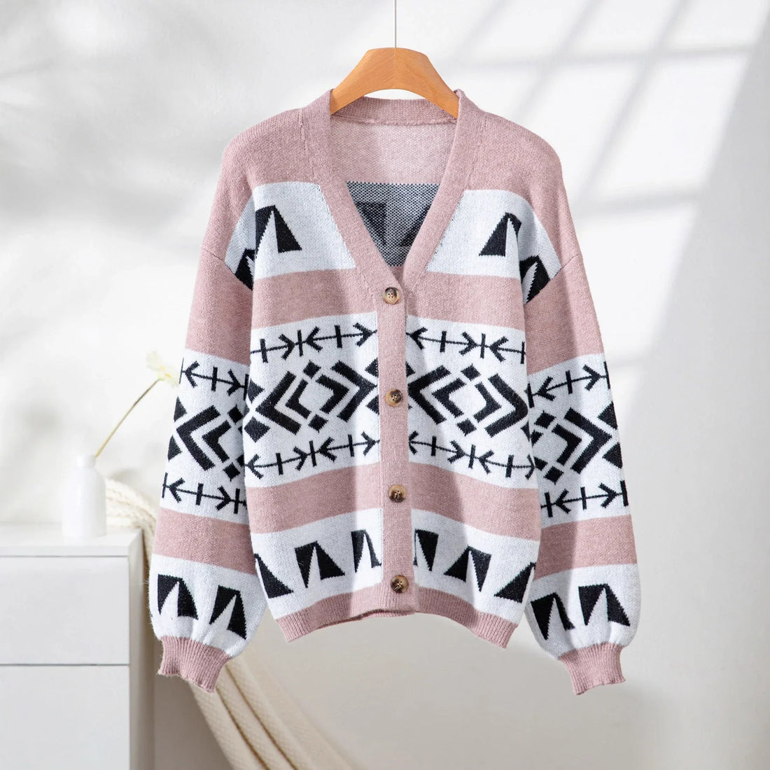 Woman wearing a pink, white, and black geometric pattern knit cardigan with balloon sleeves.