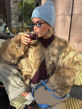 Close-up of a woman in a brown faux fur jacket holding a coffee cup