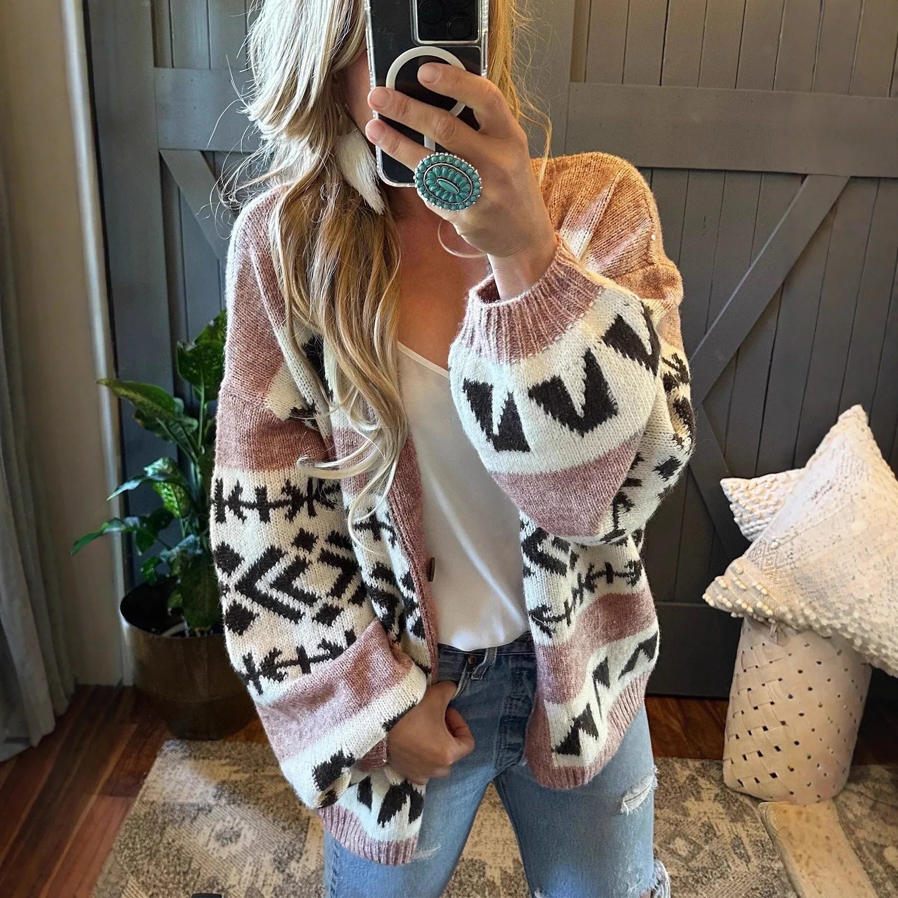 Woman wearing a pink, white, and black geometric pattern knit cardigan with balloon sleeves. Main image