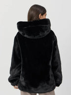 Back view of a woman wearing a black hooded faux fur jacket.