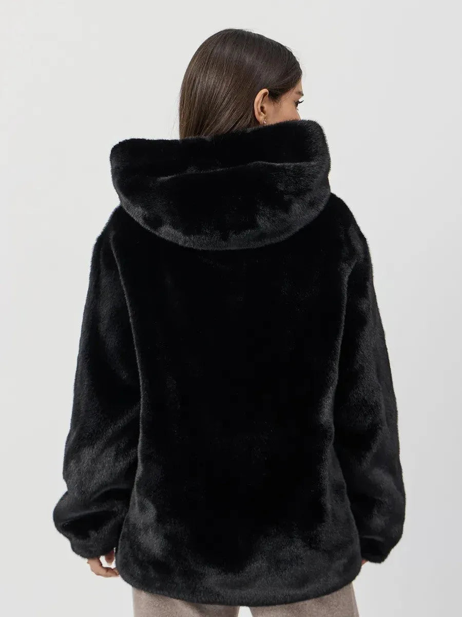 Back view of a woman wearing a black hooded faux fur jacket.