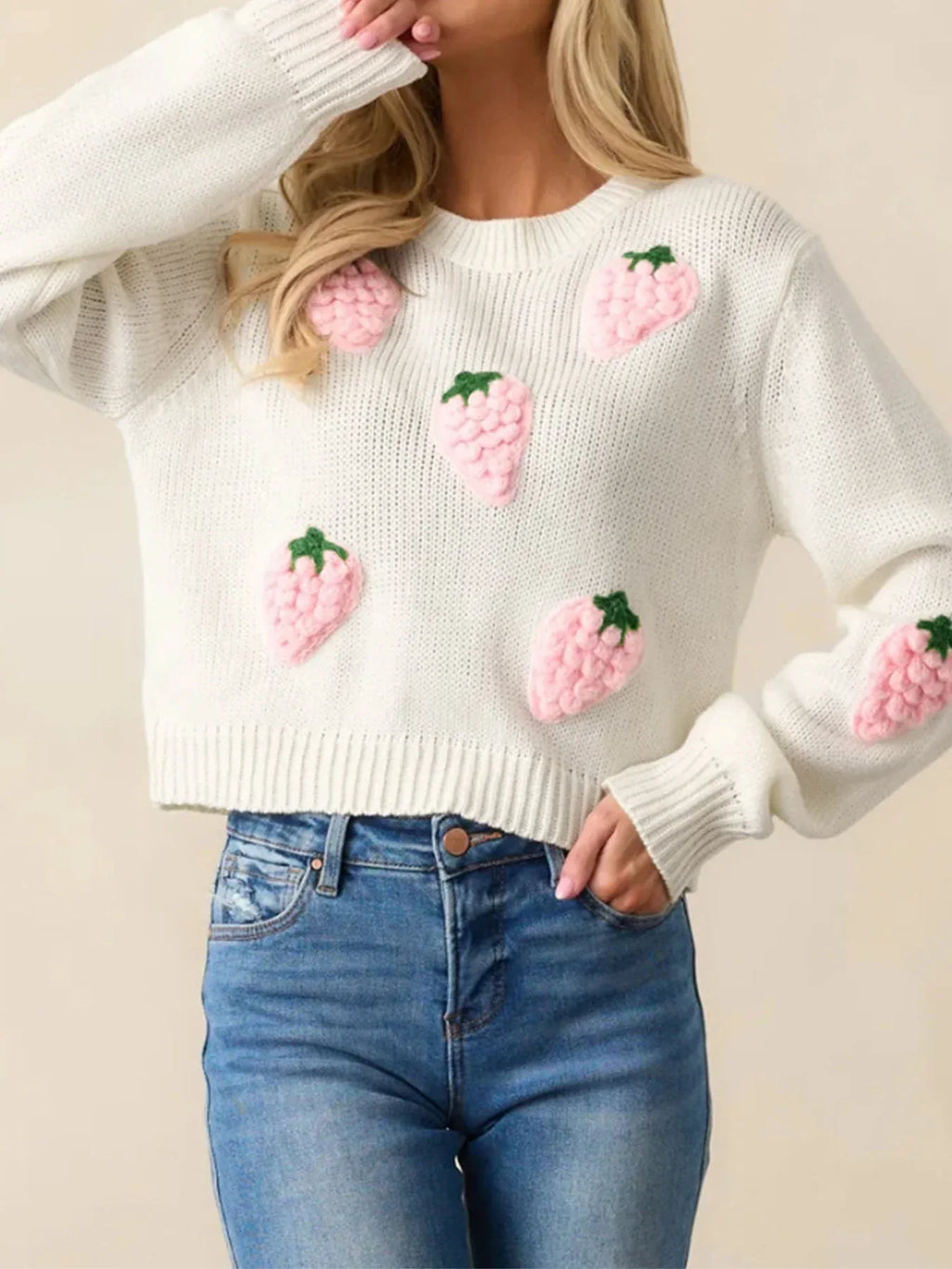 Close-up of a woman wearing a white cropped knit sweater with strawberry appliques, showcasing the texture and design.
