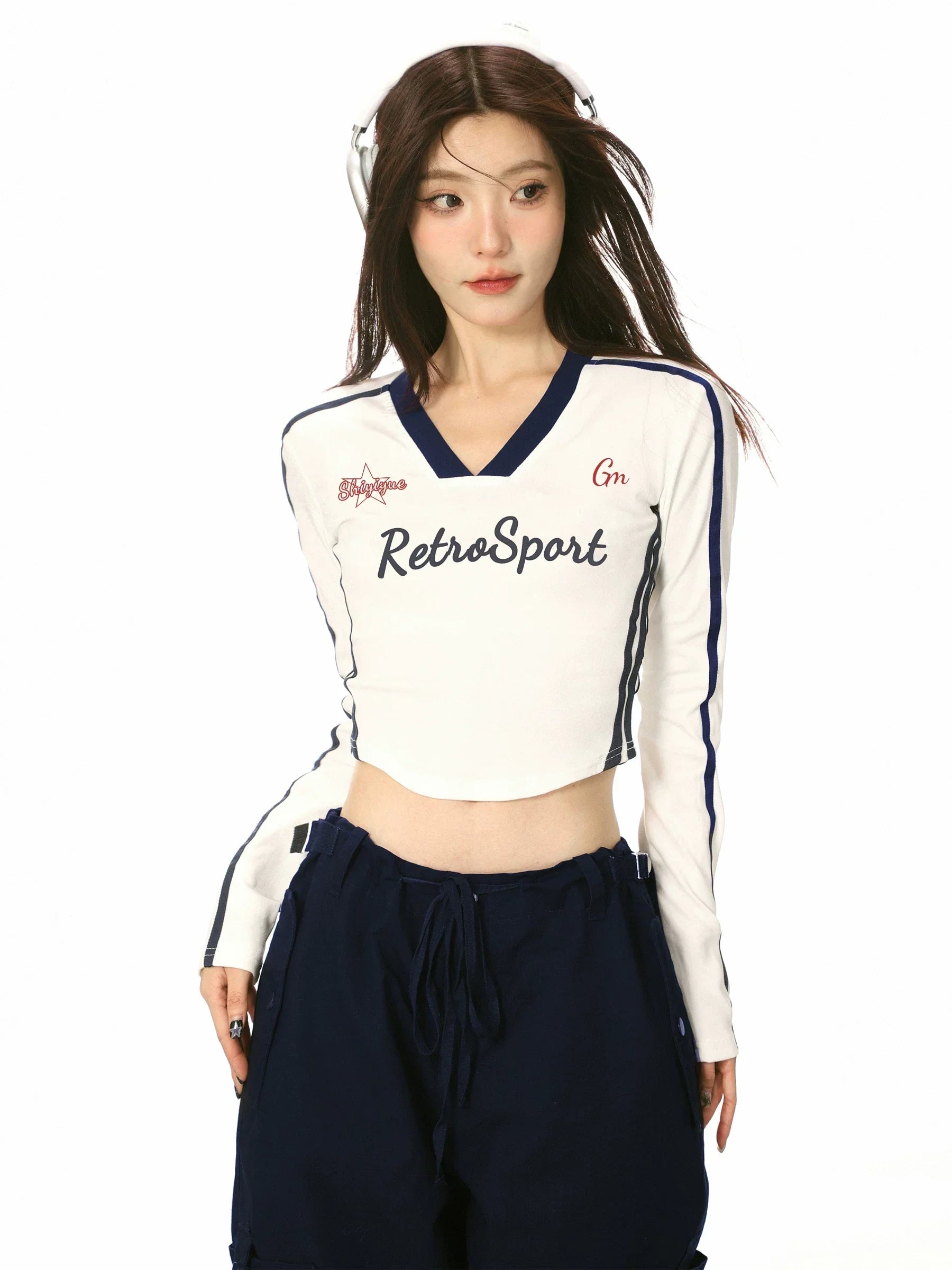 Side view of a model in a white long-sleeve crop top with navy contrast sleeves.