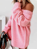 Woman in a pink oversized knit sweater with sleeves pushed up, holding a black and white bag.