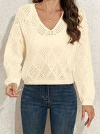Woman wearing a cream V-neck pointelle knit sweater with high-waisted jeans