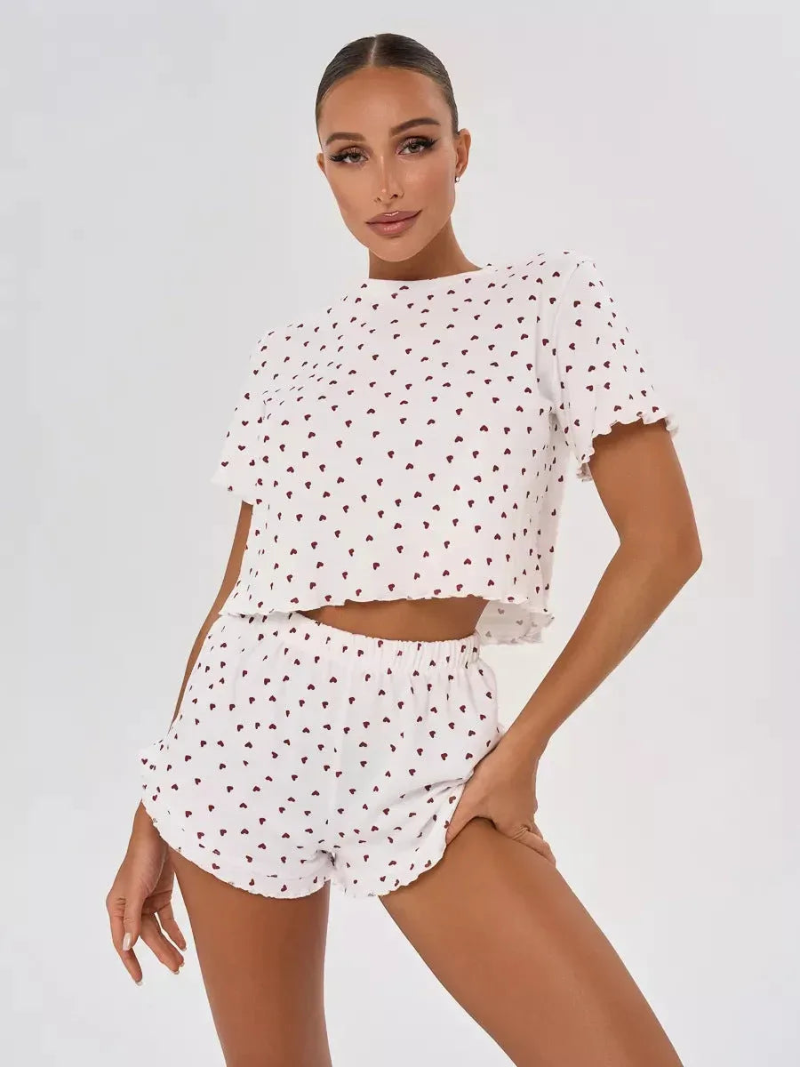 Woman wearing a white cropped pajama top and shorts with a red heart print and ruffled hems.