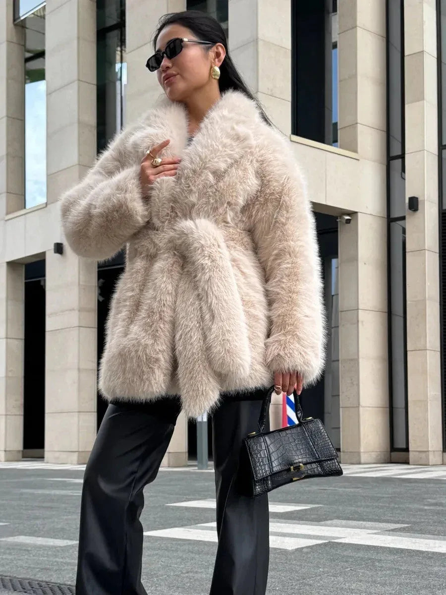 Woman wearing a cream faux fur coat with a belted waist and lapel collar. Main image