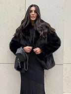 Woman wearing a black faux fur jacket over a black dress.