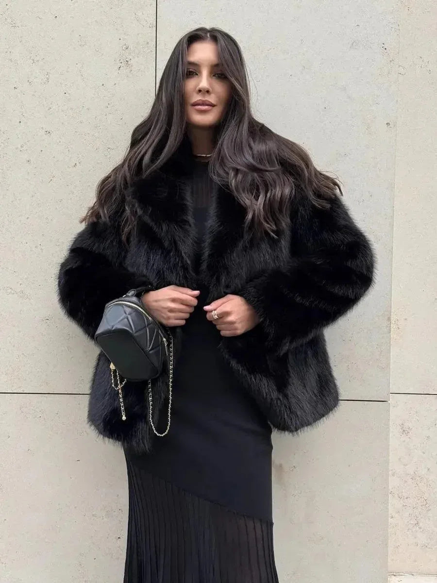 Woman wearing a black faux fur jacket over a black dress.