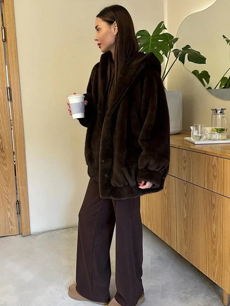 Woman in a brown faux fur hooded jacket and wide-leg pants.