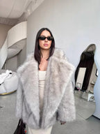 Frontal view of a woman in a grey faux fur coat, emphasizing its luxurious feel and elegant drape.