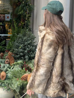 Woman from behind wearing a brown and tan faux fur jacket in front of a Christmas display.