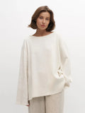 Woman in an off-white oversized knit sweater and beige pants
