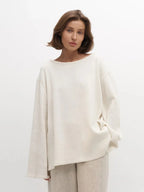 Woman in an off-white oversized knit sweater and beige pants