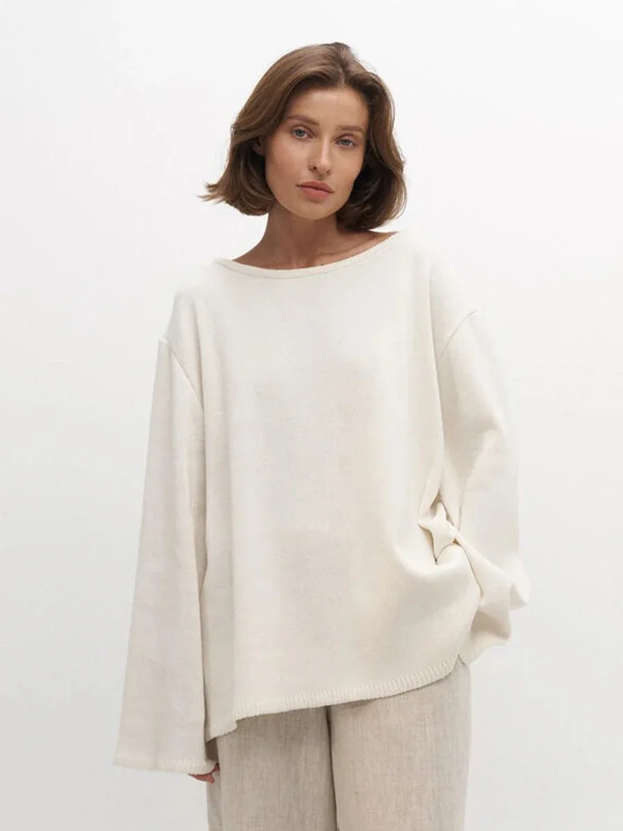Woman in an off-white oversized knit sweater and beige pants