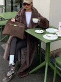 Close-up of a woman's outfit featuring a brown faux fur coat and a brown handbag.