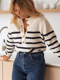 Woman leaning on a counter wearing a striped knit sweater.
