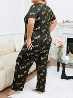 Woman wearing a black short-sleeve pajama top and pants with a gold heart and 'love' graphic print, viewed from the side.