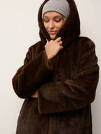 Close-up of a woman wearing a brown faux fur hooded coat and a grey beanie.