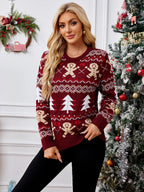 Woman wearing a burgundy knit sweater with gingerbread man and Christmas tree pattern, standing in front of a Christmas tree.