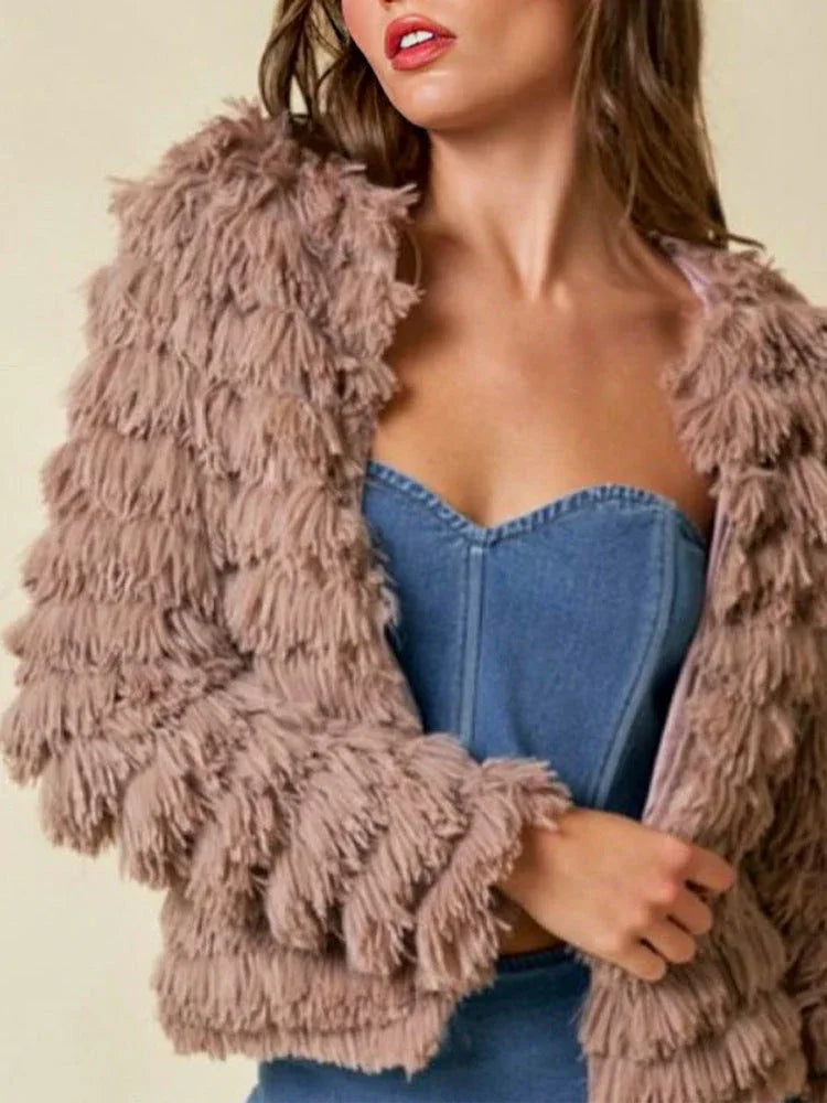 Close-up of a woman wearing a tan shaggy faux fur jacket over a blue denim bustier.