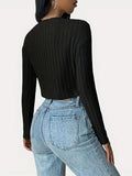 Woman wearing a black ribbed cropped long-sleeve shirt and light wash jeans, back view