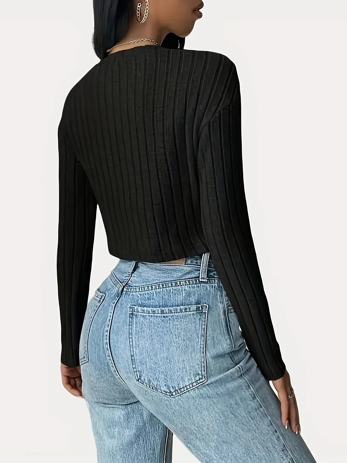 Woman wearing a black ribbed cropped long-sleeve shirt and light wash jeans, back view