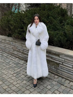 Woman wearing a long white faux fur coat with an oversized collar and matching cuffs, standing outdoors.