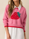 Woman wearing a pink cropped knit sweater with a strawberry graphic, showing the neckline and collar of an underlayer.