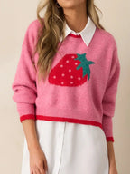 Woman wearing a pink cropped knit sweater with a strawberry graphic, showing the neckline and collar of an underlayer.