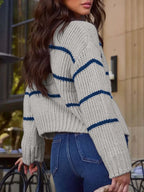 Back view of a woman wearing a cropped gray knit cardigan with navy blue stripes.