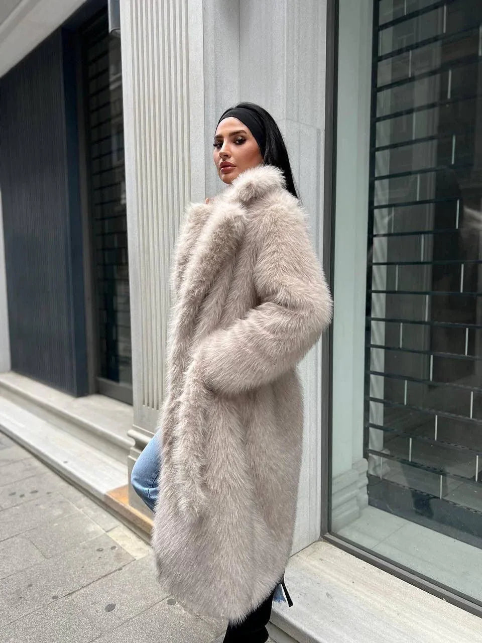 Woman in a light beige faux fur coat with lapel collar and side pockets, posing outdoors.