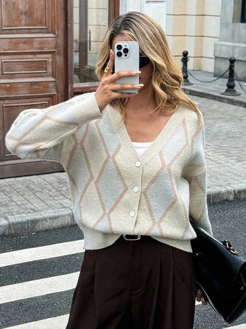 Woman wearing a cream argyle knit cardigan with a white tank top and brown pants.