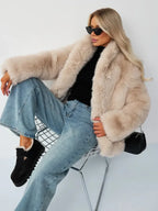 Model sitting in a chair wearing a beige faux fur cropped jacket