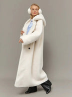 Woman wearing a long white hooded faux fur coat, showing the coat's front with a blue shirt underneath.