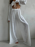 Close-up of the white sheer knit set, highlighting the V-neck tie-front top and drawstring waist pants.