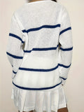 Back view of a woman in a white knit sweater with navy blue horizontal stripes.