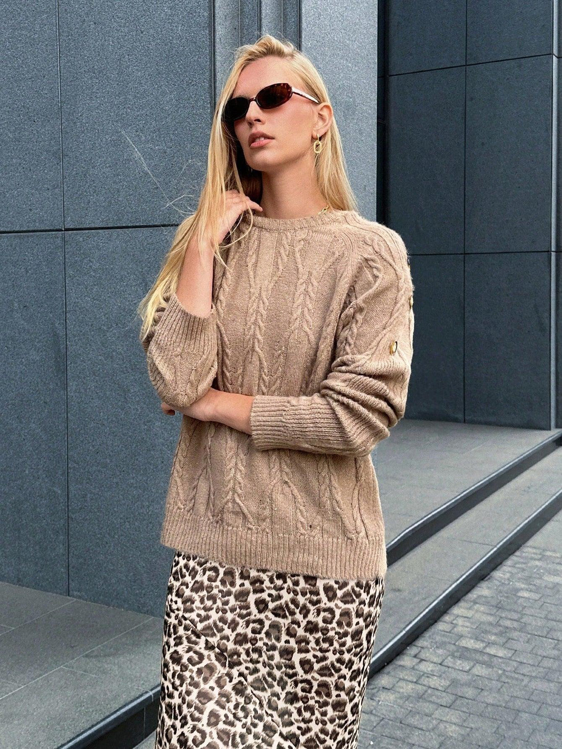 woman wearing a tan knit sweater with a textured pattern and blue jeans
